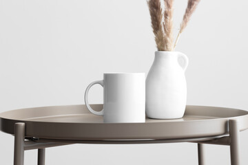 White mug mockup with a pampas decoration on the beige table.
