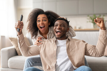 African Couple Shaking Fists Shouting While Watching Sport TV Indoor