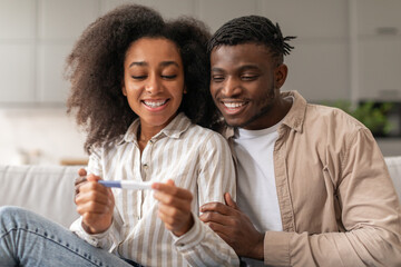 Loving Black Young Couple Holding Positive Pregnancy Test Embracing Indoor