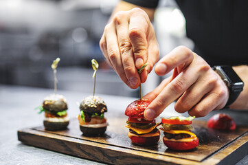 chef hand cooking set mini hamburgers, mini burgers on restaurant kitchen
