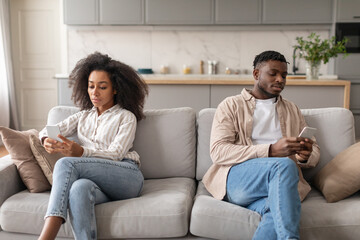 Displeased Bored African American Couple Using Smartphones Sitting At Home