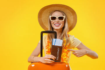 Woman going on vacation with suitcase and passport pointing over isolated yellow background....