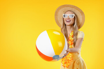 Attractive woman with beach accessories holding colorful ball on yellow background. Active holidays...