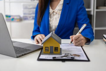 Real estate agent, young woman holding house and house keys, selling or renting property, moving house or renting property, small house, property insurance and real estate concept in office