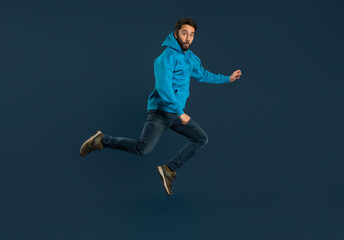Excited Young Man Man Jumping In Air On Blue Background