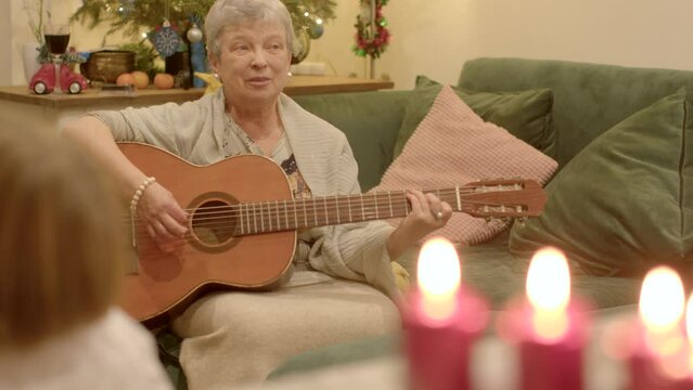Guitar accompaniment and Christmas songs adds a special celebratory element to the festive occasion, captivating audience with magic of music during joyous time of year. Woman with guitar in real life