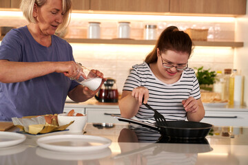 Fototapeta na wymiar Down syndrome woman and her mother preparing breakfast together