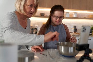 Down syndrome woman and her mother using recipe on the phone