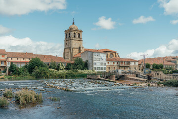 Fototapeta na wymiar Tower of a gothic church near the river on a summer day. Aguilar de Campoo, Spain