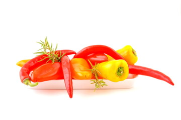 Peppers on white plate, on white background. Red, orange and yellow vegetables.