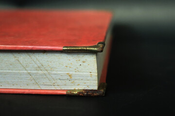 An old book with an orange cover on a black table. Old books piled up in a heap, close-up, learning and education concept.