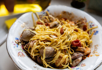 Seafood pasta with clams and shrimp on floral plate