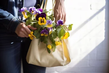 Fotobehang person holding a bag with sunlit pansies © studioworkstock