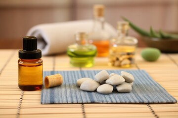 Fototapeta na wymiar essential oils and massage stones on bamboo mat