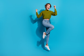Fototapeta na wymiar Full length photo of positive optimistic girl wear trendy clothes raise fists yes hooray empty space isolated on cyan color background