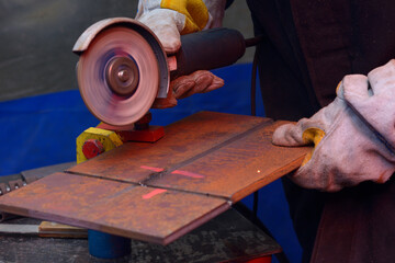 Welder hands grinding metal piece with a grinder, processing weld after welding, workshop