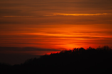 Orange solar disk seen above the forest. Wonderful sunset at the end of day