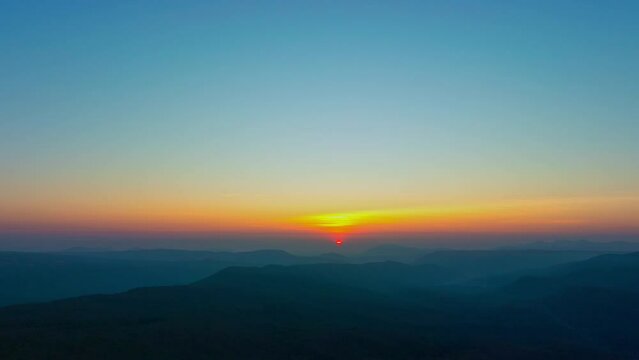 Aerial hyper lapse view The sweet sky of dawn shines through the mountains..Mountains Embracing the Beauty of a Sunrise, .Painting a Stunning Landscape with the Play of Colors, Clouds, and forest.