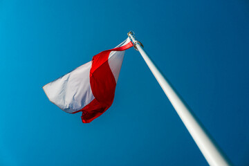 Polish flag waving on a mast on a background of blue sky