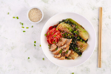 Stir fried of chicken, sweet peppers and bok choy in a bowl on the table. Stir fry pak choi. Asian food. Top view