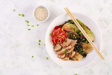 Stir fried of chicken, sweet peppers and bok choy in a bowl on the table. Stir fry pak choi. Asian food. Top view