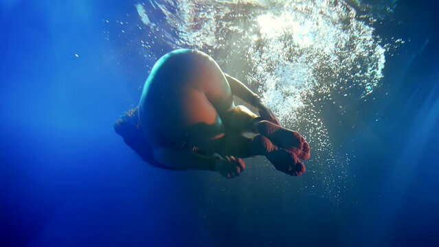 In an underwater dream, a woman in her silver jumpsuit seems to float in weightlessness, like a mermaid in a cosmic dance, surrounded by psychedelic light.