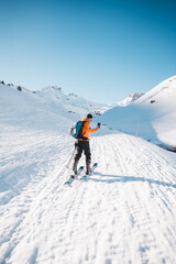 Naklejka na ściany i meble A man on ski alpine tour throught snowy Alps in Switzerland or Austria, Backcountry skier in Alps