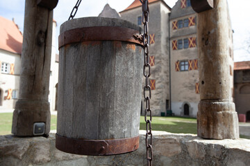 A rustic wooden bucket swings gently from a sturdy chain, gracing the front of the building with...