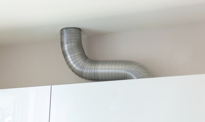 Expandable aluminium corrugated ventilation pipe in kitchen connecting a cooker hood and a ventilation air shaft.