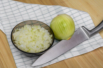 Surowa biała cebula w całości i rozdrobniona pokrojona nożem kuchennym leży na kuchennym blacie