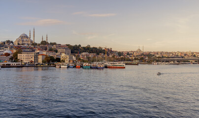 Fototapeta premium Istanbul, Turkey - 09.10.2022: View of the embankment, water and ships in the city of Istanbul on a summer day. Big ferry ship sail at Bosphorus strait, mosques of Fatih area seen on back.