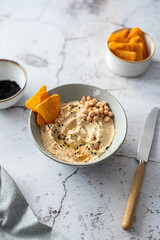 hummus with chips in a gray bowl on a light background