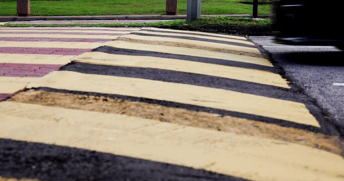Car slowing down at speed bump or road hump painted in yellow and black stripe.