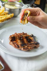 pouring lemon to a grilled chicken steak