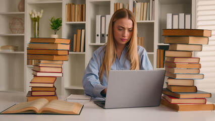Busy Caucasian student girl stressed leaner pupil woman studying with laptop and books homework learning online search information knowledge problem prepare for test exam study at university library