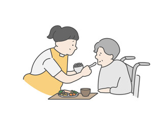 高齢女性の食事介助をする女性介護士
