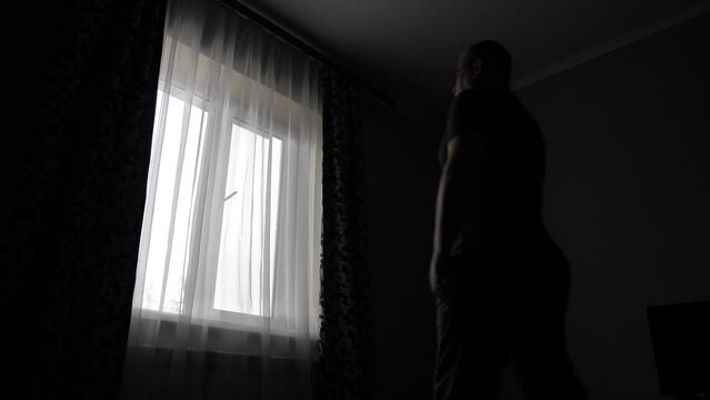 The man draws the dark curtains and does not allow light into the room.