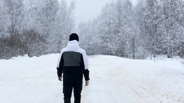 A young man walking in on a snow-covered road, trees covered with snow, winter, Russia, Smolensk region