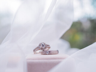 Obraz premium Diamond engagement wedding rings on bridal veil. Wedding accessories. Valentine's day and Wedding day concept.