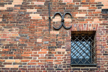 Small barred window in an old brick wallin Torun.  The metal bars on the window. 