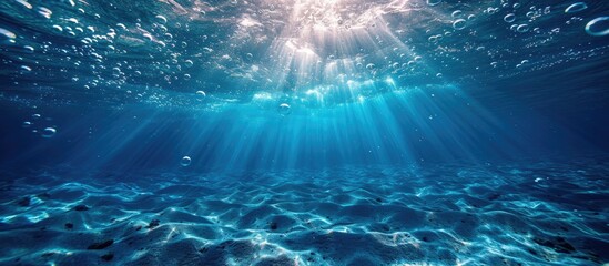Underwater bubbles allow sunlight to penetrate the azure ocean depths dark blue.  - obrazy, fototapety, plakaty
