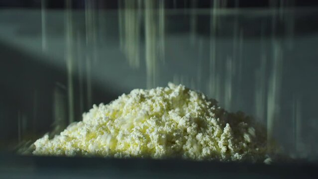 Cottage cheese, curd at a dairy factory falls from the whey separation and cooling machine onto the packaging line. Automatic line for the production of curd and cheese.