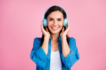 Portrait of toothy beaming satisfied woman wear stylish clothes touching headphones listen music...