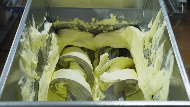Milk processing, butter production at a dairy factory. Thick butter from a metal basin enters the dosing machine. Ready-made thick butter at an organic natural products factory.