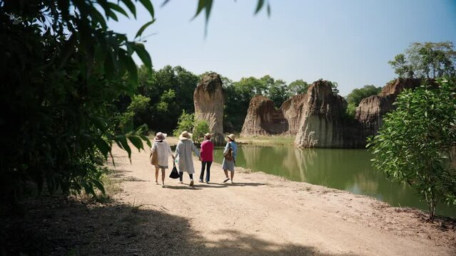 Backside scenes are four elderly women are best friends, go out play go hiking, Walking among nature with many interesting things, woman wears cover-up protect herself from hot sun