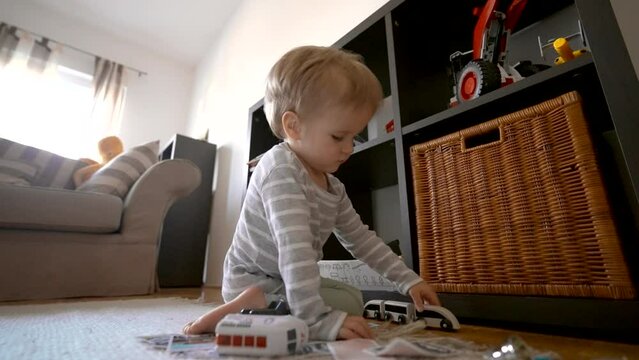 Watch as a curious baby explores their world, savoring the delights of imagination while playing with a toy truck on the floor.