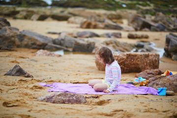 Adorable preschooler girl playing on the beach at Atlantic coast of Brittany, France