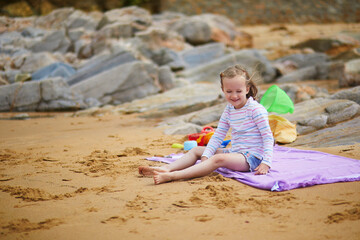 Adorable preschooler girl playing on the beach at Atlantic coast of Brittany, France