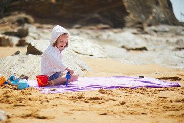 Adorable preschooler girl playing on the beach at Atlantic coast of Brittany, France