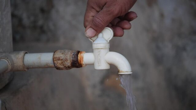 Closeup slow-motion shot of human hand closing white water tap